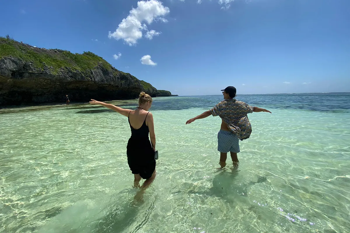 Couple walking in the turquoise shallows of a Zanzibar beach