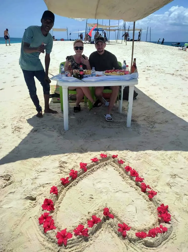 Heart of flower petals on a sandbank set up for a romantic lunch in Zanzibar
