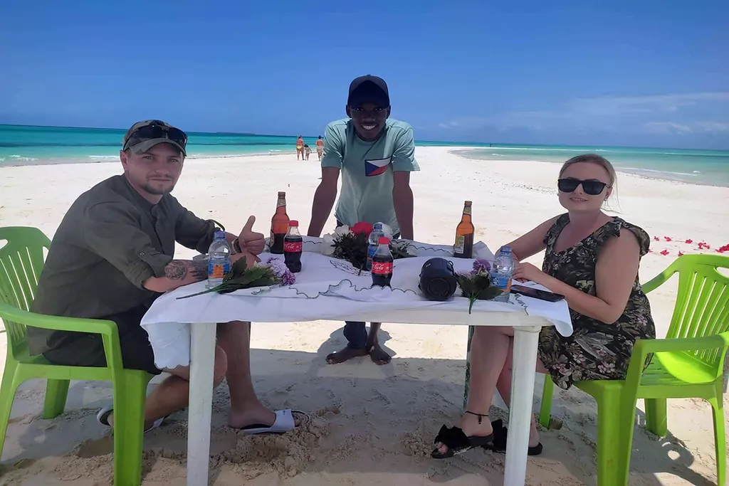 Guests enjoying a table lunch on a white sandbank during a Zanzibar boat tour