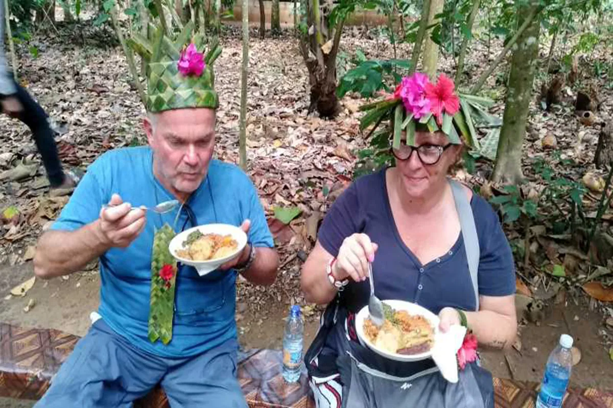 Guests eating lunch in palm-leaf hats after a Zanzibar spice tour