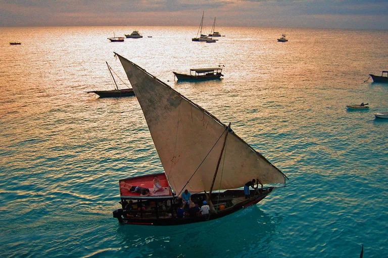 Traditional dhow sailing in golden evening light off Zanzibar